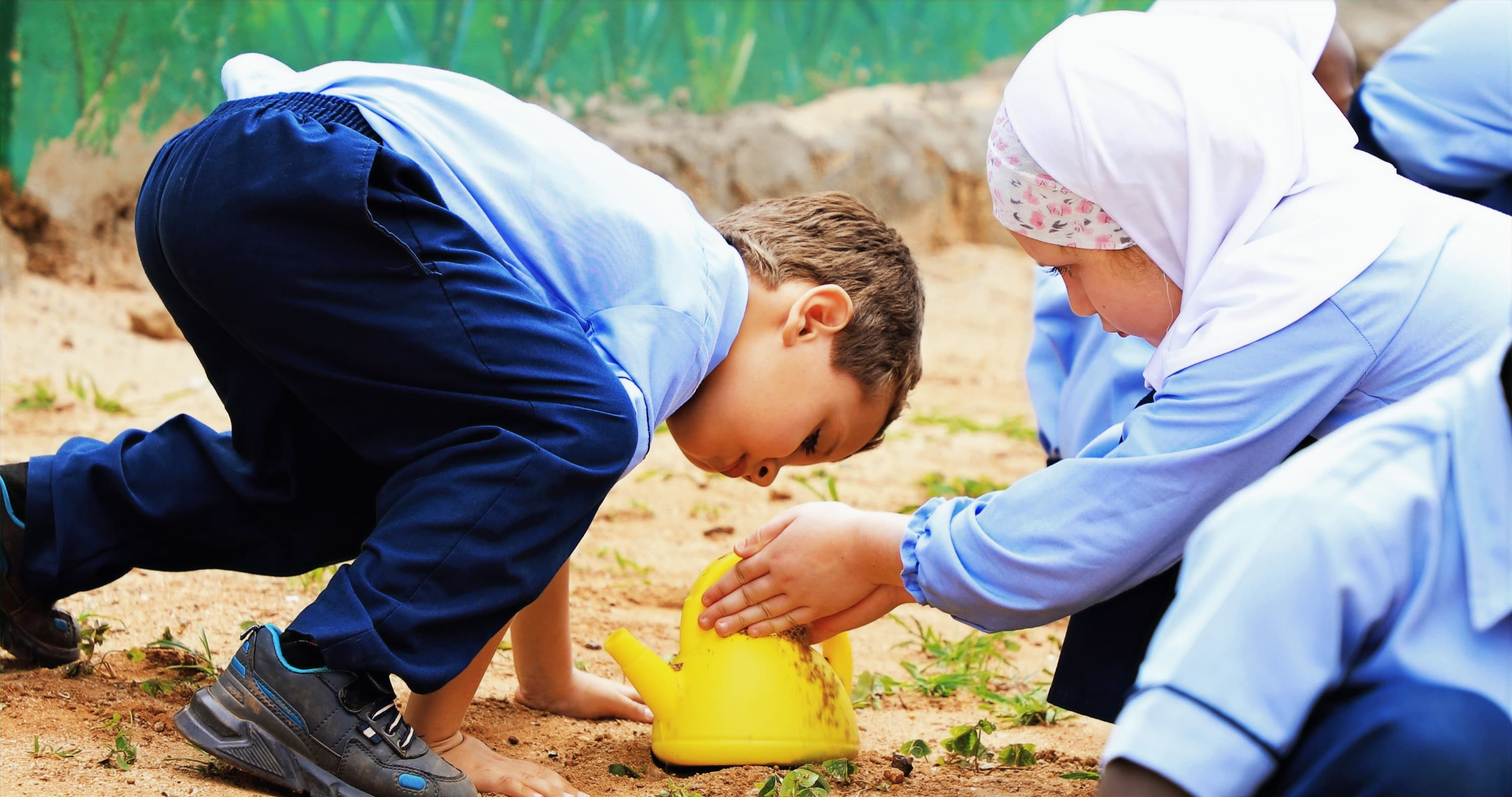 Two Tamayuz Junior School pupils in uniform planting in the school garden