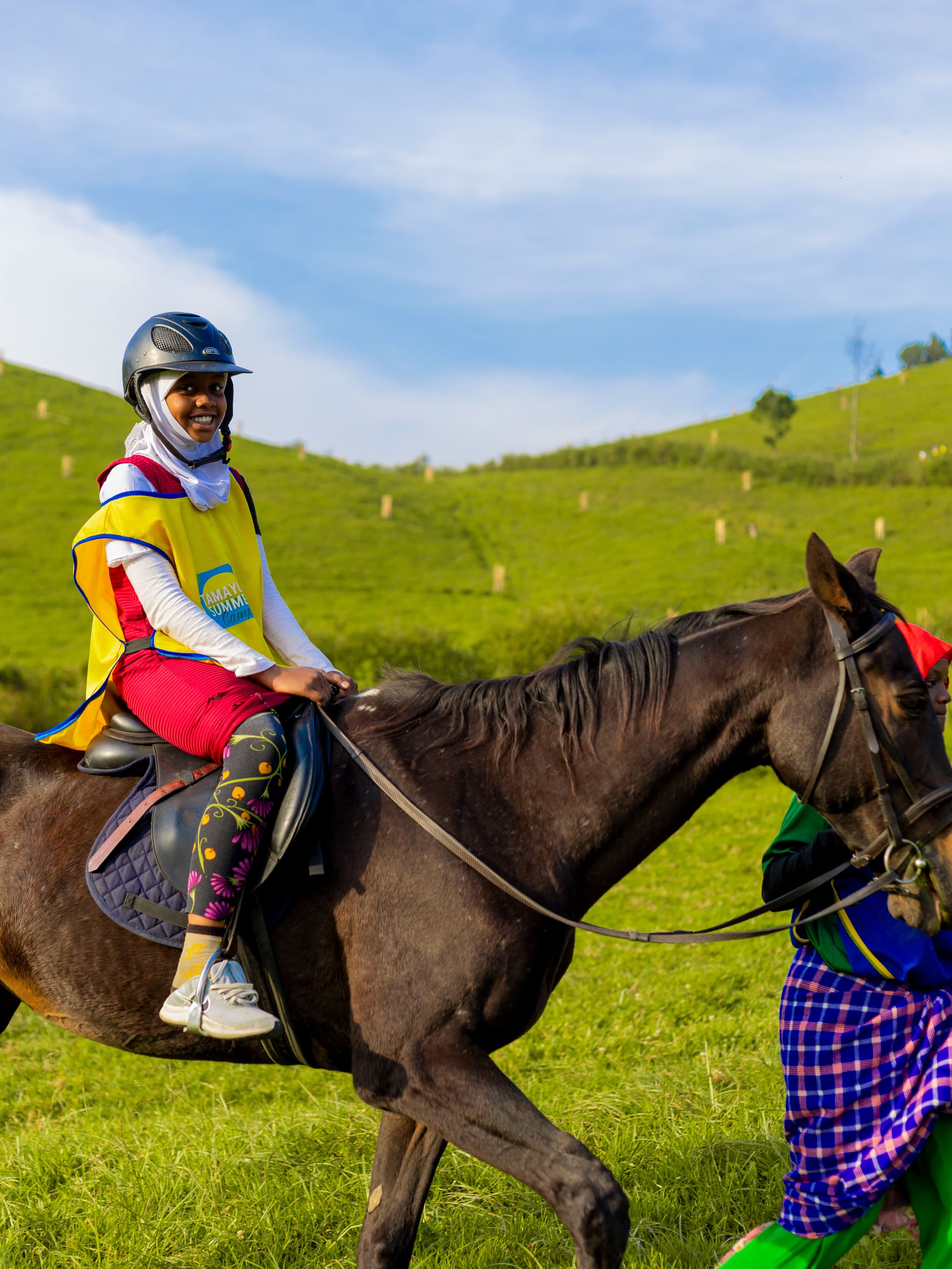 A Tamayuz Summer Camp student riding a horse in riding gear